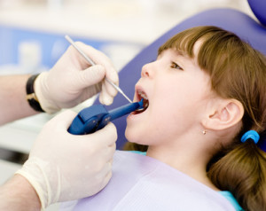 Kids Dentist using a dental filling gun