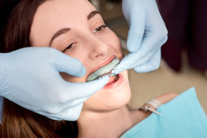 Making imprint of teeth with dental capa to young woman patient in the dental office